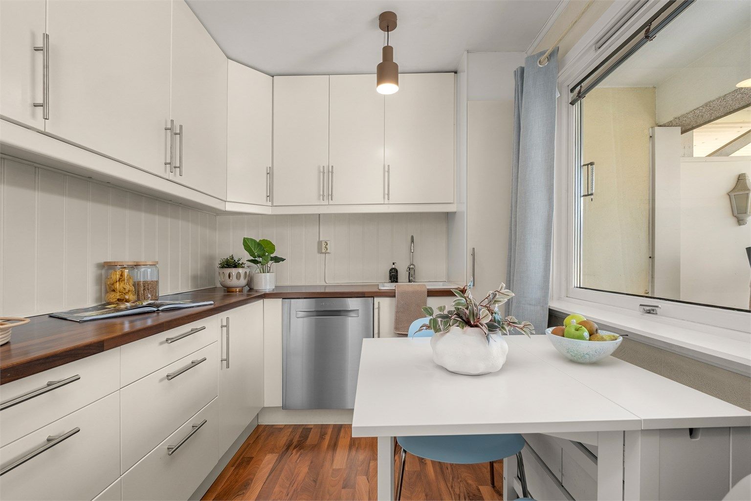 Kjøkkenet ligger naturlig tilbaketrukket fra stuen og er innredet med lyse slette flater og benkeplate av laminat. 