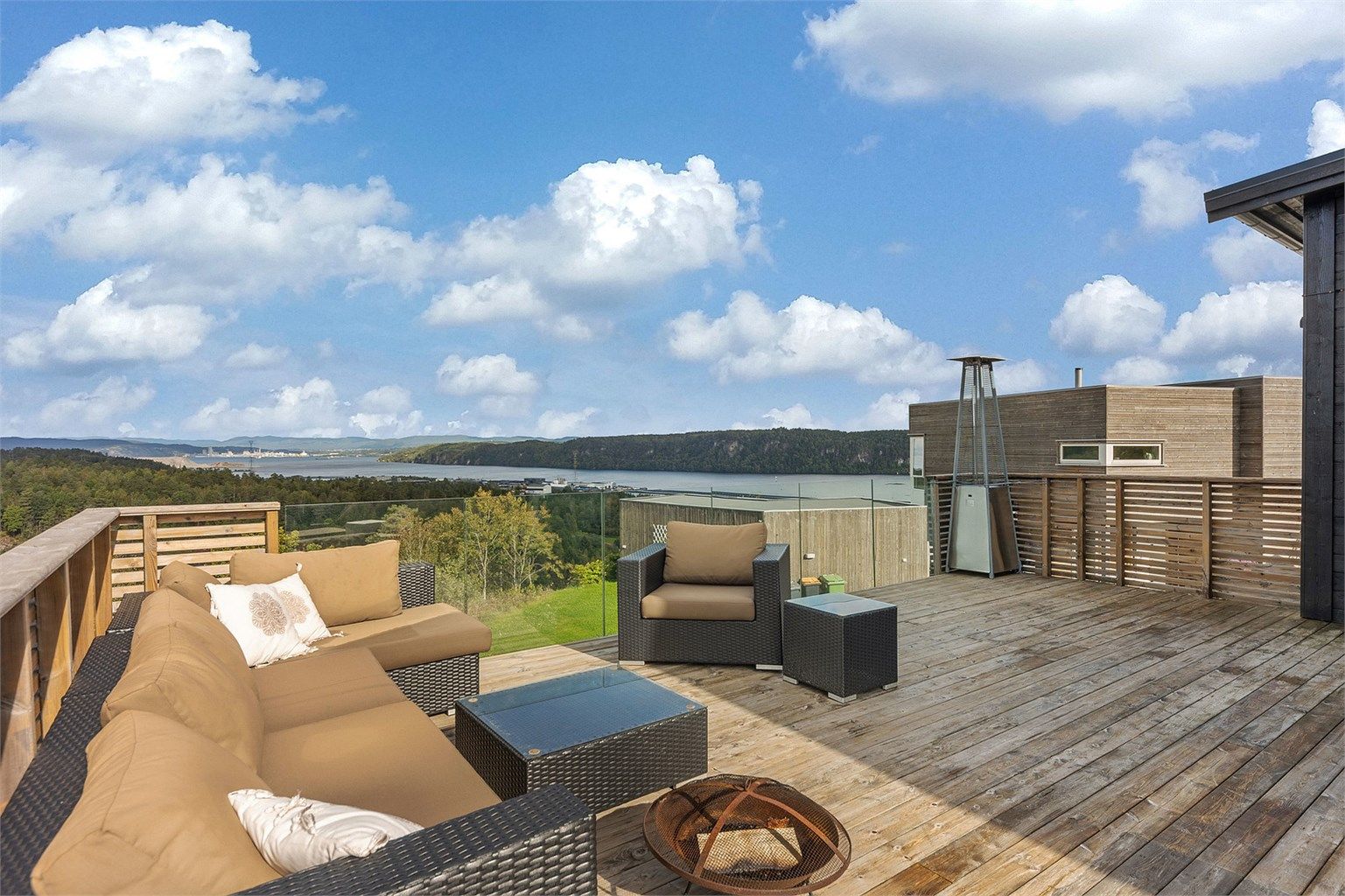 Den store terrassen utenfor stuen har rikelig med plass til flere sittegrupper. Rekkverk mot sjøen i glass for at utsikten kan nytes også når du sitter ned.