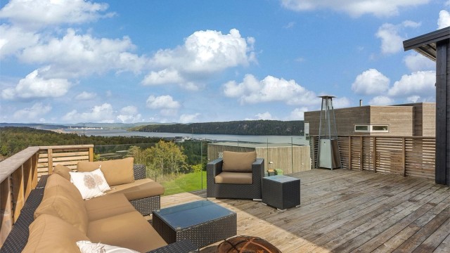 Den store terrassen utenfor stuen har rikelig med plass til flere sittegrupper. Rekkverk mot sjøen i glass for at utsikten kan nytes også når du sitter ned.