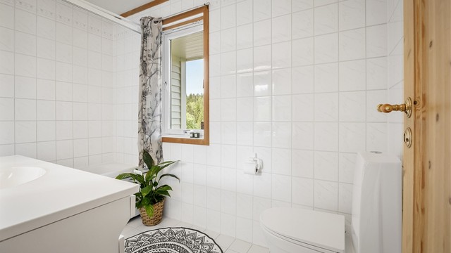 Rommet har flislagte vegger og et gulvstående toalett.