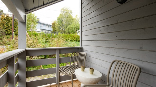 Overbygget inngangsparti med flislagt repo og behagelige sitteplasser i ly for været.
