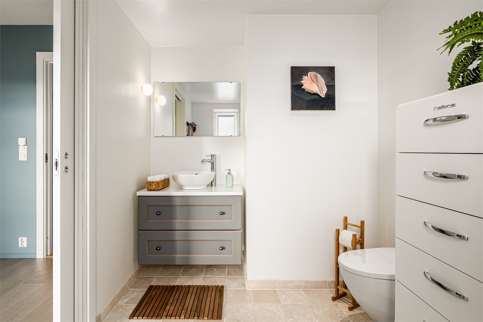 Badet er pent flislagt på gulv, med malte overflater på veggene. Det er gulvvarme, og himlingen har malt, slett flate med downlights.