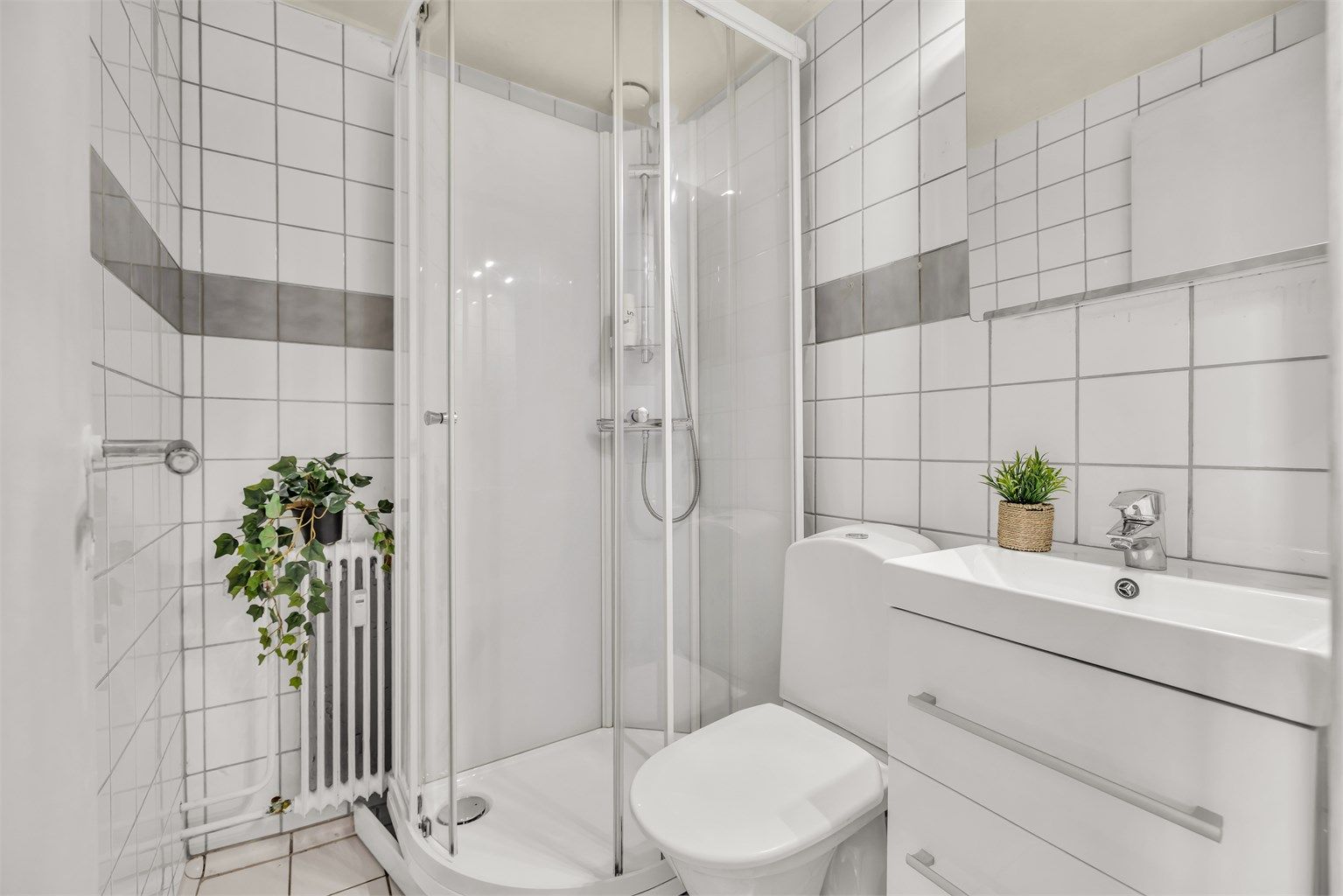 Badet ble oppgradert i 2020 med nytt dusjkabinett, nytt toalett, vegghengt servantinnredning med ovenpåliggende servant og speilskap med overlys.