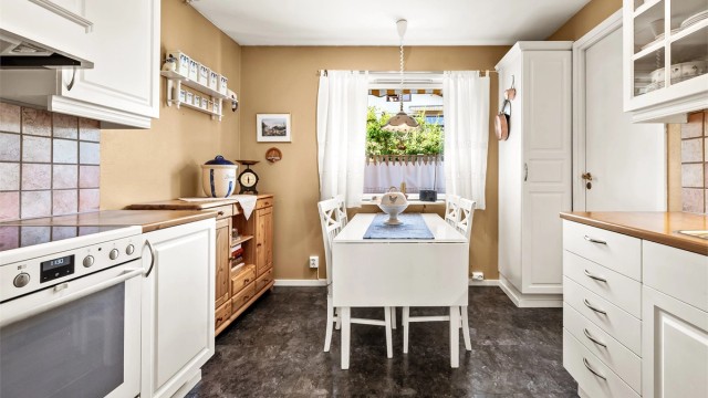 Lys kjøkkeninnredning med profilerte fronter og benkeplate med laminert overflate.