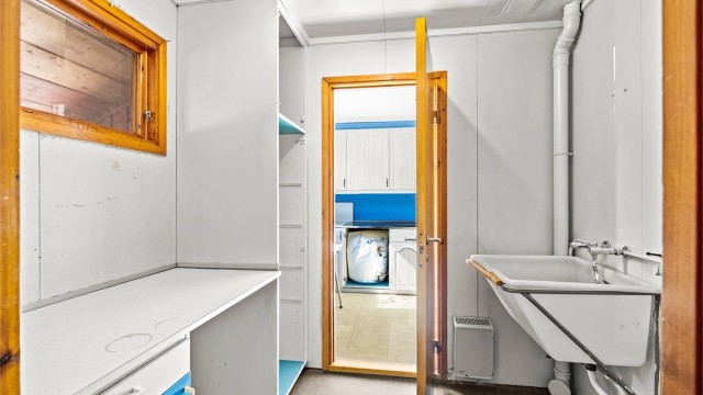 Eget vaskerom med utslagsvask i plast og opplegg for vaskemaskin.