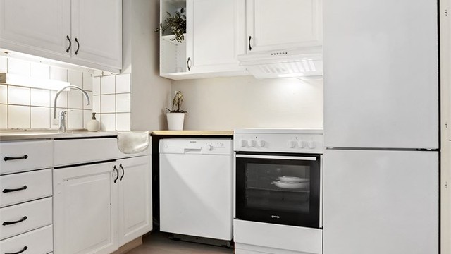 Kjøkkeninnredning med profilerte fronter og benkeplate i laminat og rustfritt stål.