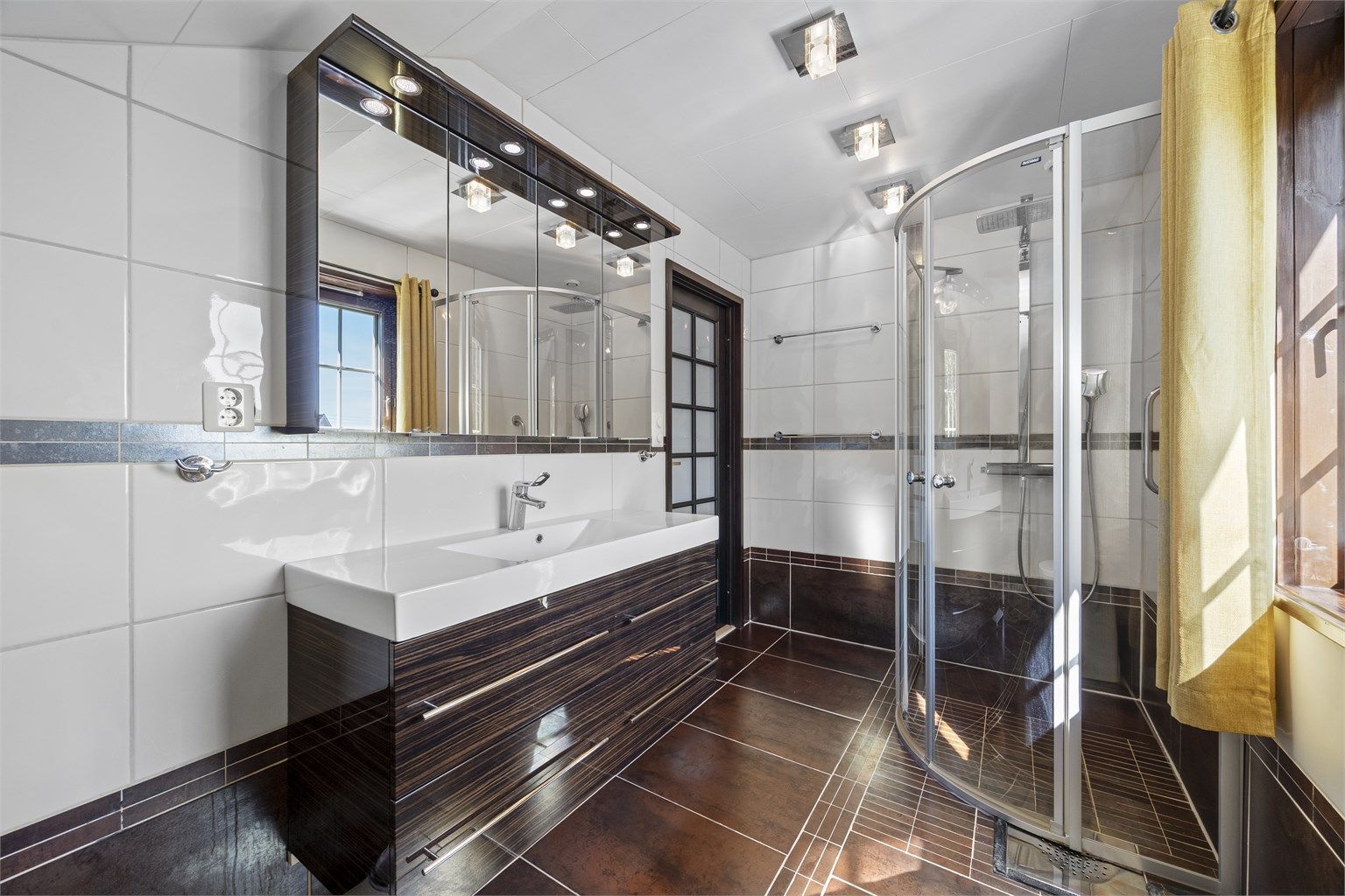Badet i loftsetasjen har flislagt gulv med gulvvarme og dusjnisje med glassdør.