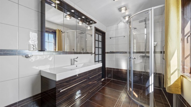 Badet i loftsetasjen har flislagt gulv med gulvvarme og dusjnisje med glassdør.