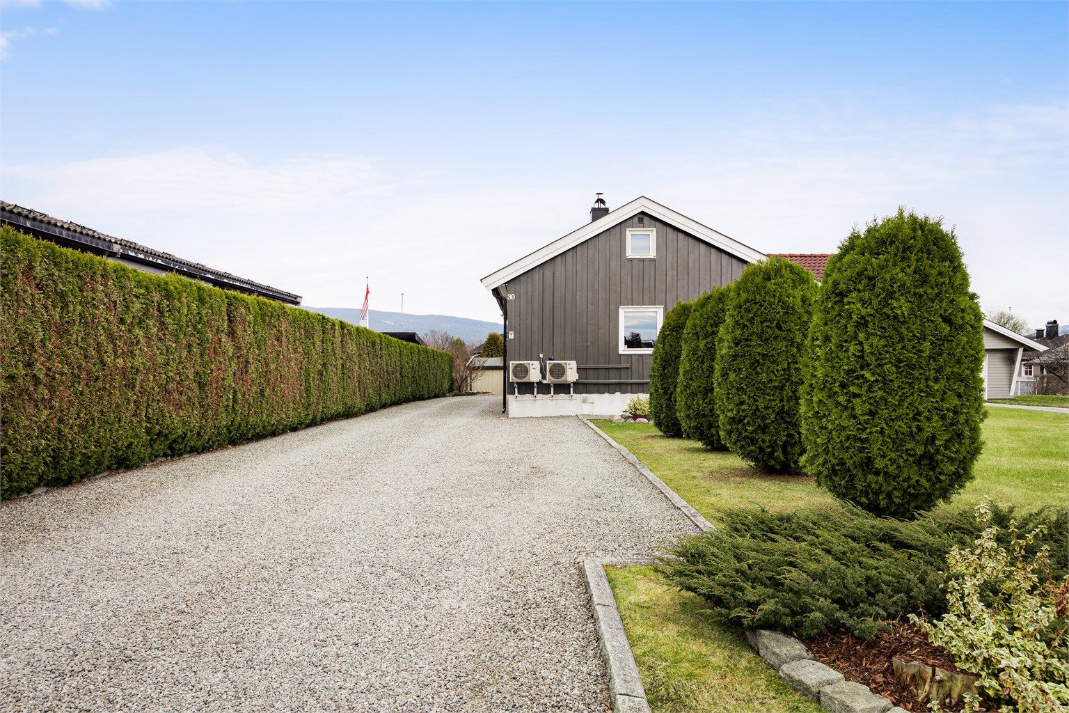 Parkering på egen gruset gårdsplass. Lader for elbil er montert på husvegg. 