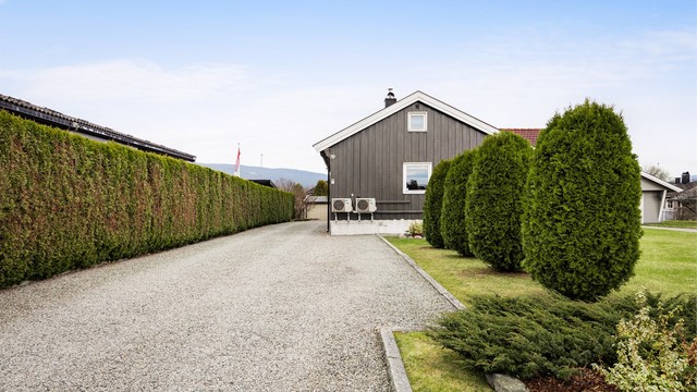 Parkering på egen gruset gårdsplass. Lader for elbil er montert på husvegg.