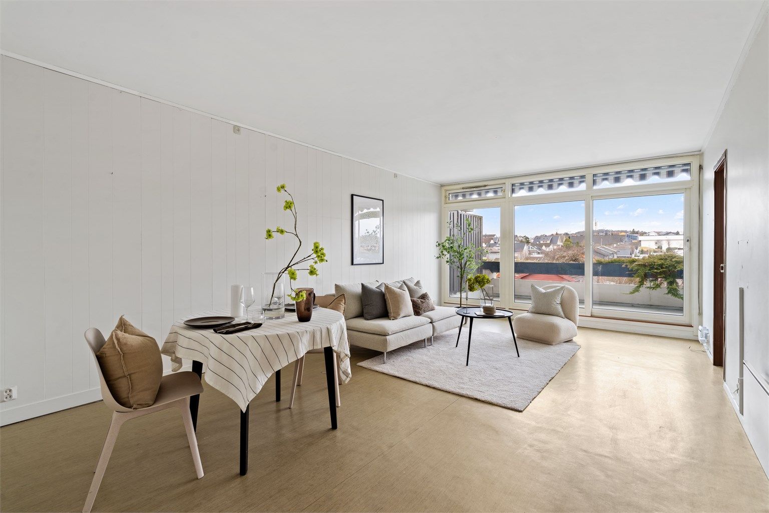 Stuen er lys og romslig, med store vindusflater og god plass til både sofagruppe og spisebord.