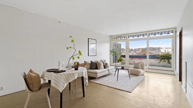 Stuen er lys og romslig, med store vindusflater og god plass til både sofagruppe og spisebord.