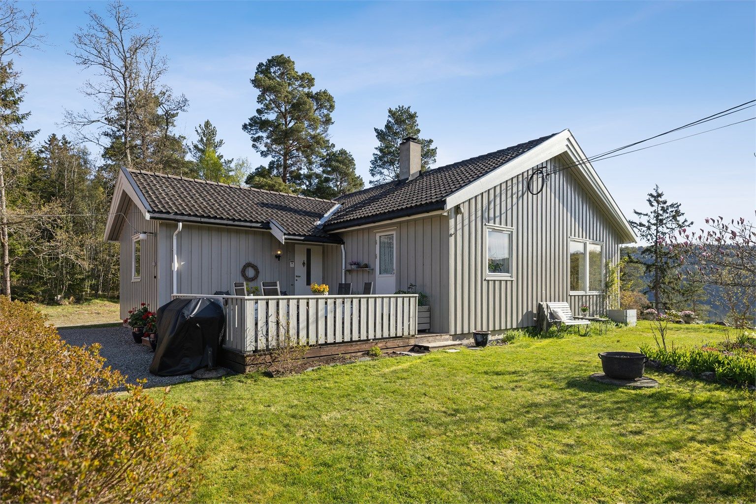 Terrasse ved inngangspartiet og en pent opparbeidet hage gir boligen et attraktivt og innbydende uttrykk fra første blikk.