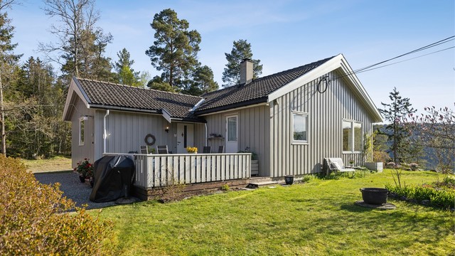 Terrasse ved inngangspartiet og en pent opparbeidet hage gir boligen et attraktivt og innbydende uttrykk fra første blikk.