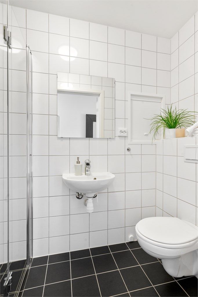 Bad I er helfliset med varme i gulv. Det er dusj, vegghengt toalett og servant. Stort speil med innfelt lys på vegg. Det er mørke fliser på gulv og lyse på vegg. 