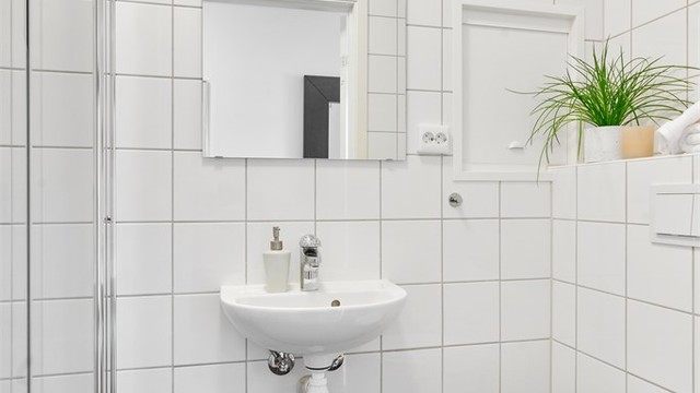 Bad I er helfliset med varme i gulv. Det er dusj, vegghengt toalett og servant. Stort speil med innfelt lys på vegg. Det er mørke fliser på gulv og lyse på vegg.