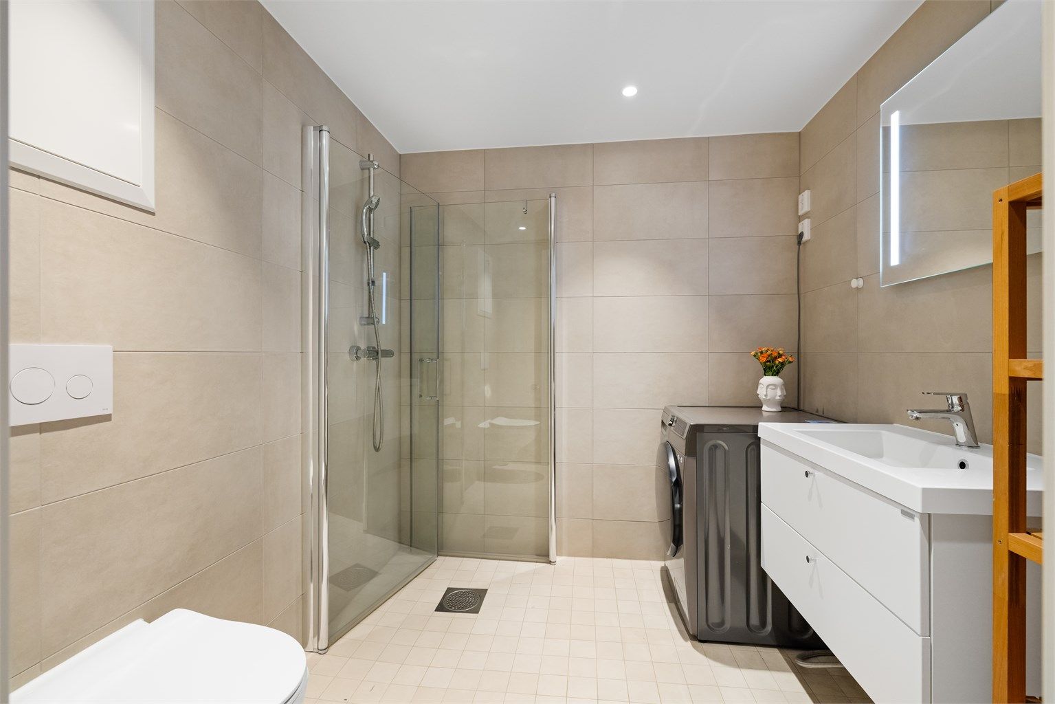 Her er det dusjnisje med innfellbare glassdører, vegghengt toalett og opplegg for vaskemaskin.