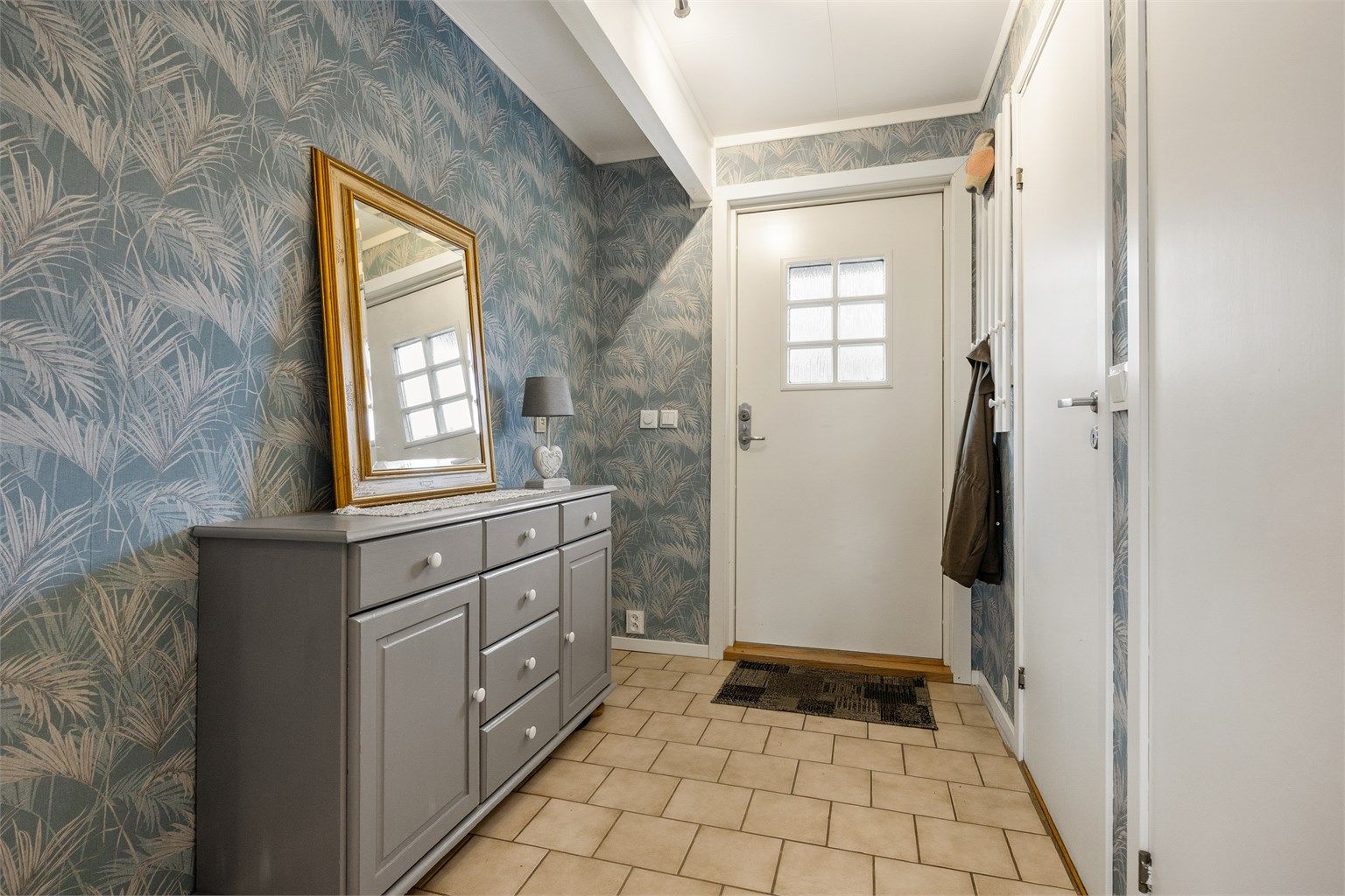 Velkommen inn. Entréen har praktiske fliser på gulvet og god plass til oppbevaring.