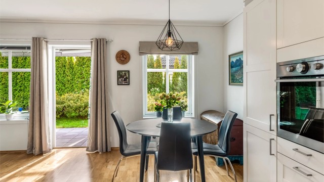 Spiseplassen ligger lyst til ved vinduet, med utsyn til hagen og direkte utgang til terrassen.