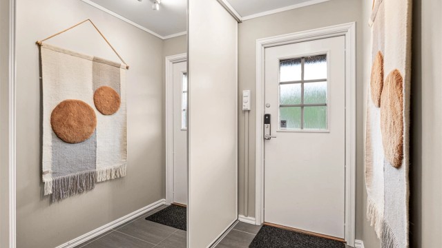 Velkommen inn i en romslig og praktisk entré - plassbygget garderobeløsning med speil og skyvedør.
