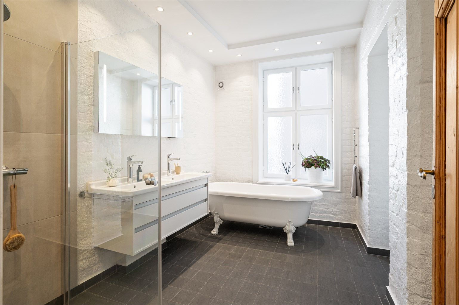 Badet er innredet med vegghengt servantinnredning, heldekkende dobbel servant, speil med integrert belysning, vegghengt toalett og opplegg for vaskemaskin.