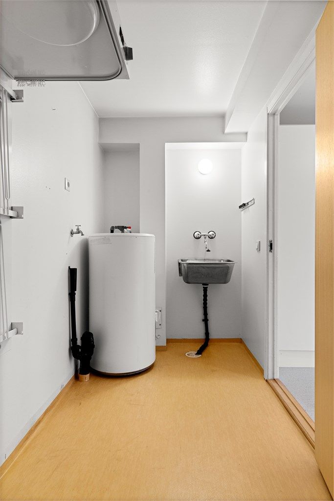Praktisk separat vaskerom med utslagsvask, opplegg for vaskemaskin og varmtvannsbereder.