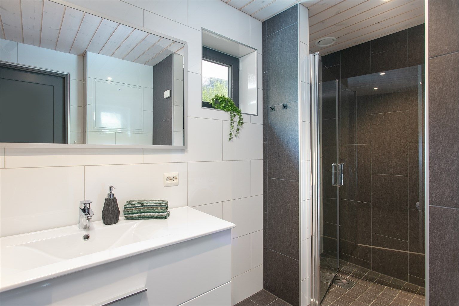 Badet er innredet med vegghengt toalett, innfelte spotter i tak og opplegg for kombinert vaskemaskin/tørketrommel som medfølger