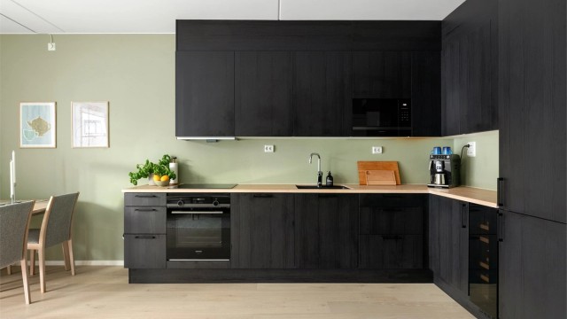 Kjøkkenet har glatte finérdører i mørk brunt eikemønster, med benkeplate i lys eik med underlimt oppvaskkum