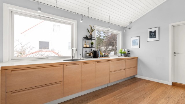Rikelig med benkeplass og store vinduer gjør kjøkkenet til en lys og funksjonell arbeidsplass.