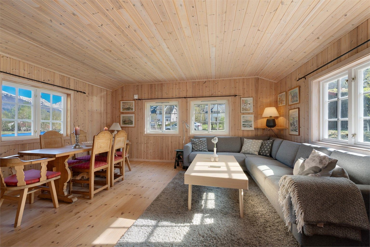 Stuen i hytta har åpen løsning mot kjøkkenet, med hvitpigmentert panel og gulv av heltre plank.