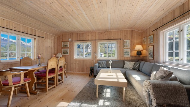 Stuen i hytta har åpen løsning mot kjøkkenet, med hvitpigmentert panel og gulv av heltre plank.