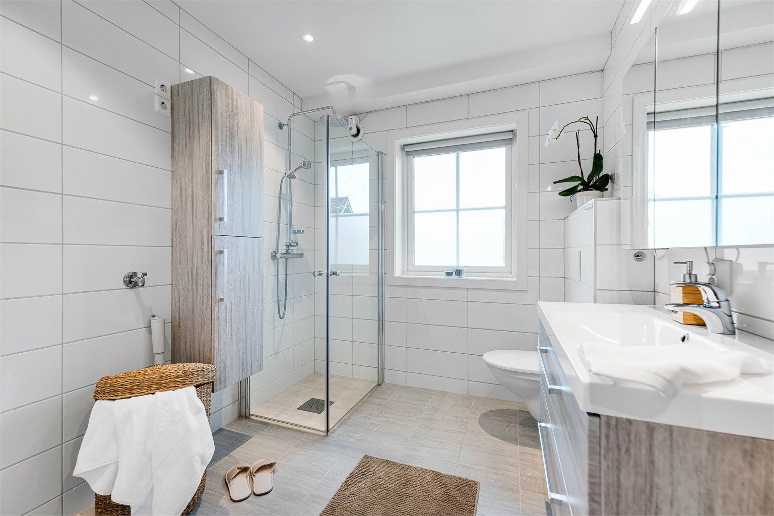 Badet er romslig, og er innredet med baderomsmøbler, vegghengt wc og dusjhjørne med dører. Gode oppbevaringsmuligheter både i speilskap, underskap og høyskap. Opplegg for vaskemaskin.