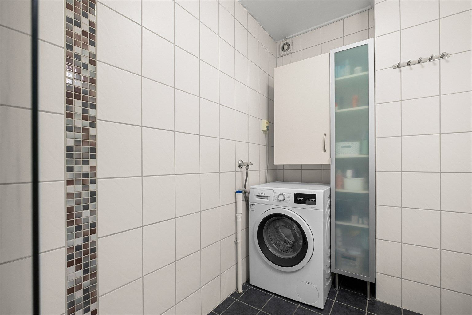 Videre er badet utstyrt med servantskap med speil og lys, badekar med vegghengt badekararmatur samt sideskap. 