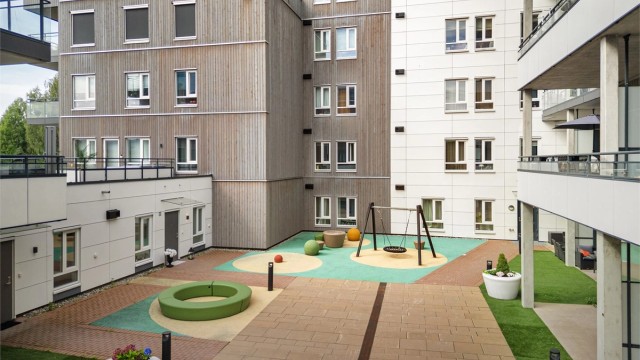 Felles bakgård med hellelagte områder, sitteplasser, lekeapparater og diverse beplantning