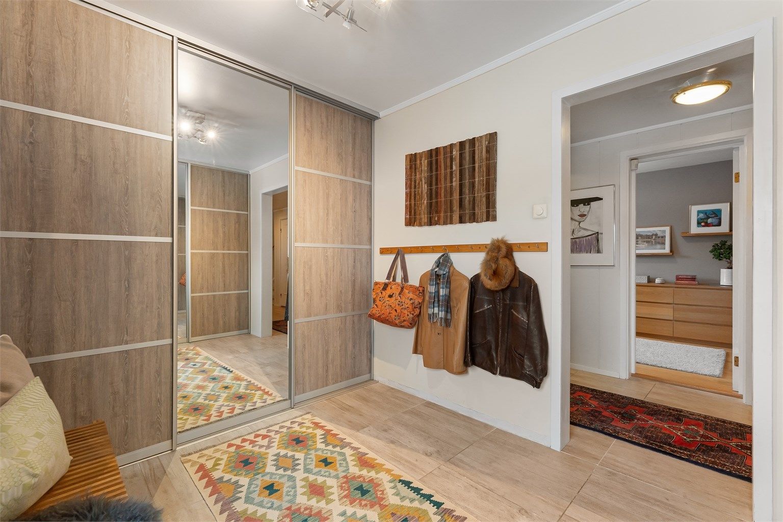 En romslig garderobe med skyvedører gir gode oppbevaringsmuligheter ved inngangspartiet.