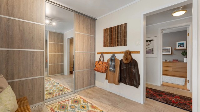 En romslig garderobe med skyvedører gir gode oppbevaringsmuligheter ved inngangspartiet.