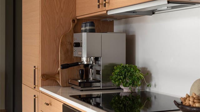 Benkeplate av stein med integrert platetopp og belysning under overskapene.