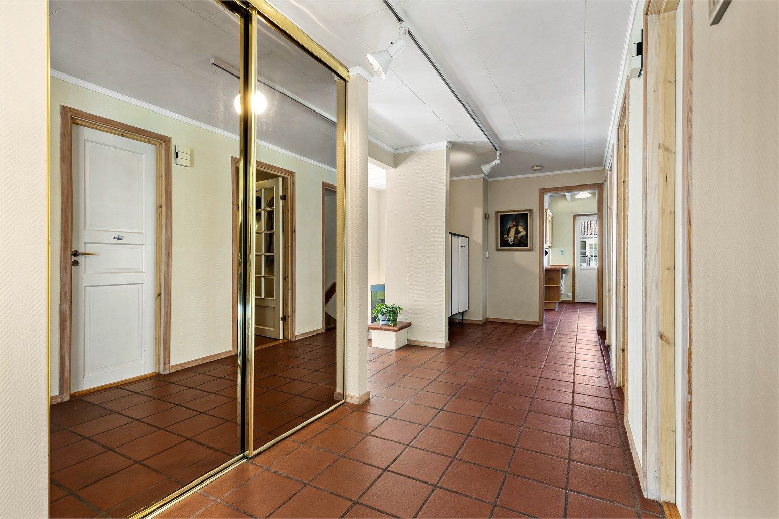 Boligens entré har god plass til oppbevaring av yttertøy og sko. Hallen er romslig med skyvedørsgarderobe. Fra hallen kommer man til kontor, begge stuene og kjøkken, samt trappegang opp til annen etasje og ned til kjeller