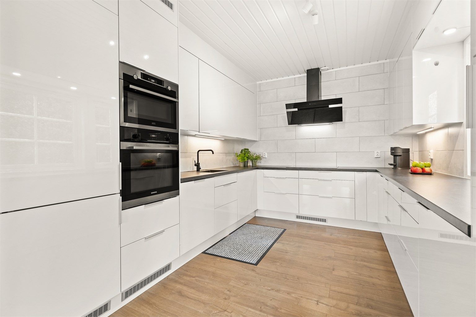 Kjøkken har hvite glatte fronter og laminert benkeplate.