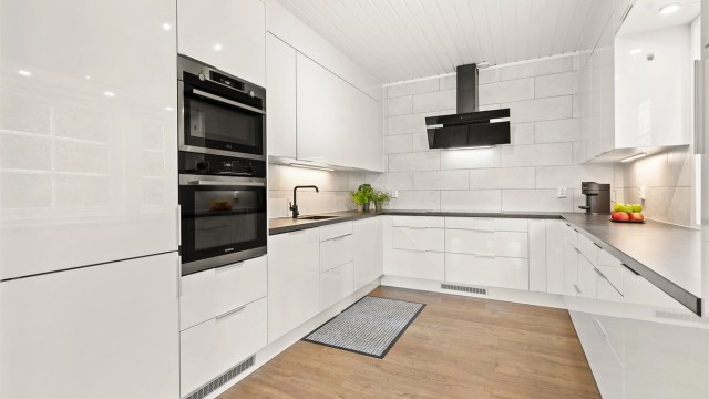 Kjøkken har hvite glatte fronter og laminert benkeplate.