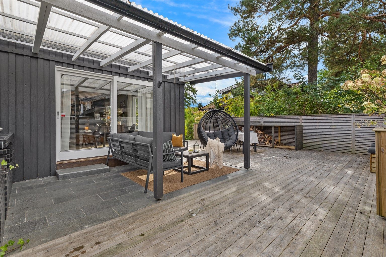 Skjermet del av terrassen med fliser og takoverbygg.