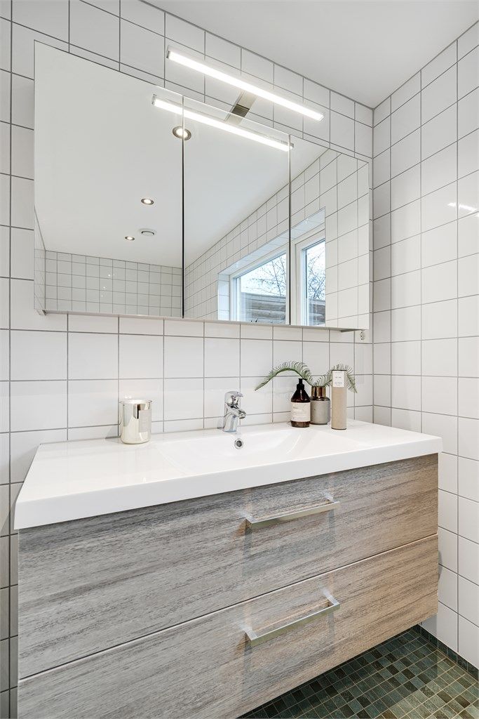 Baderomsinnredning med nedfelt servant og speilskap med integrert belysning.