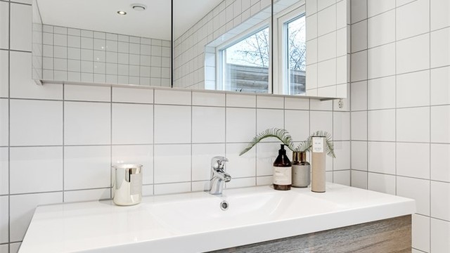 Baderomsinnredning med nedfelt servant og speilskap med integrert belysning.