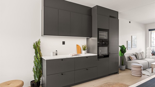 Leilighetens kjøkken er moderne og består av slette fronter og en laminert benkeplate.