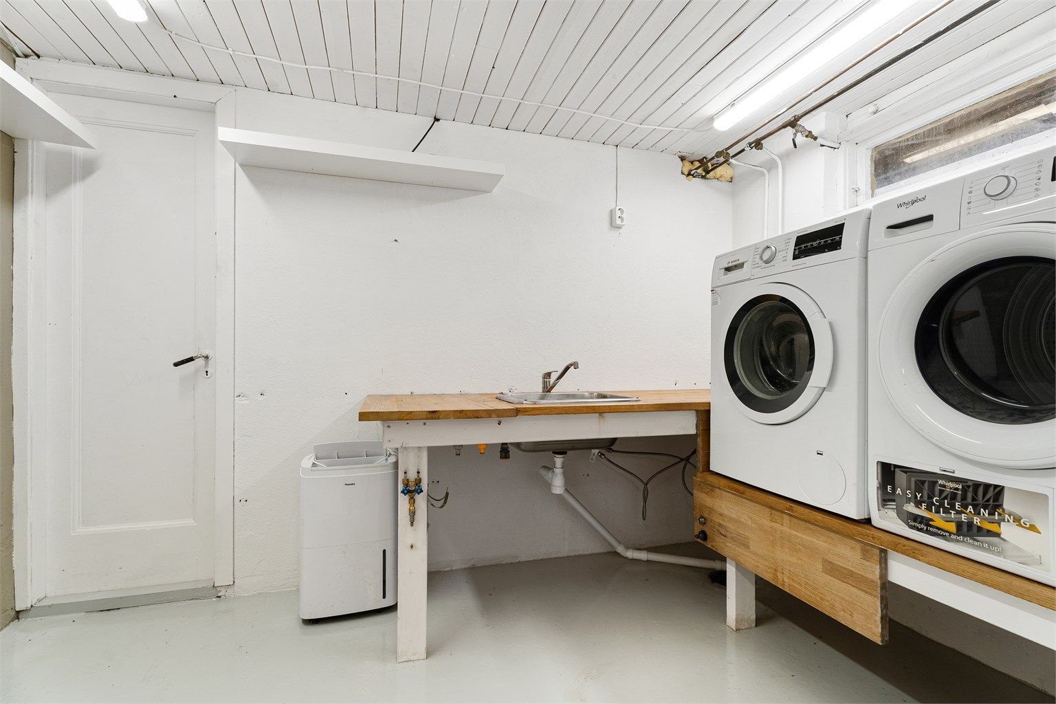 Våtrom/Vaskerom: Vaskerom fra byggeår, med malt betonggulv og malte veggflater Utslagsvask i benkeplate med to-greps armatur
