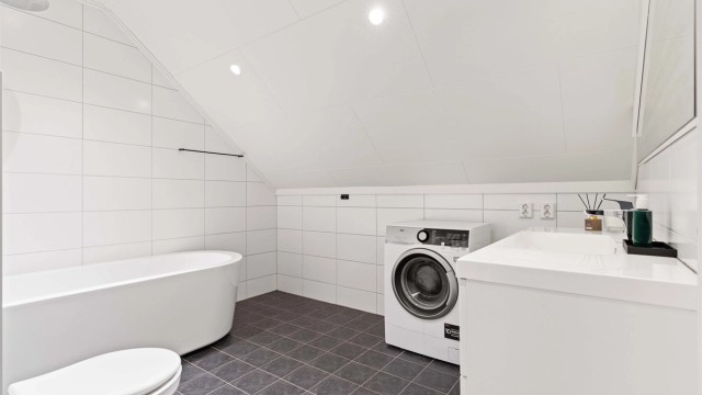 Badet i loftsetasjen er utstyrt med et frittstående badekar for ekstra velvære.