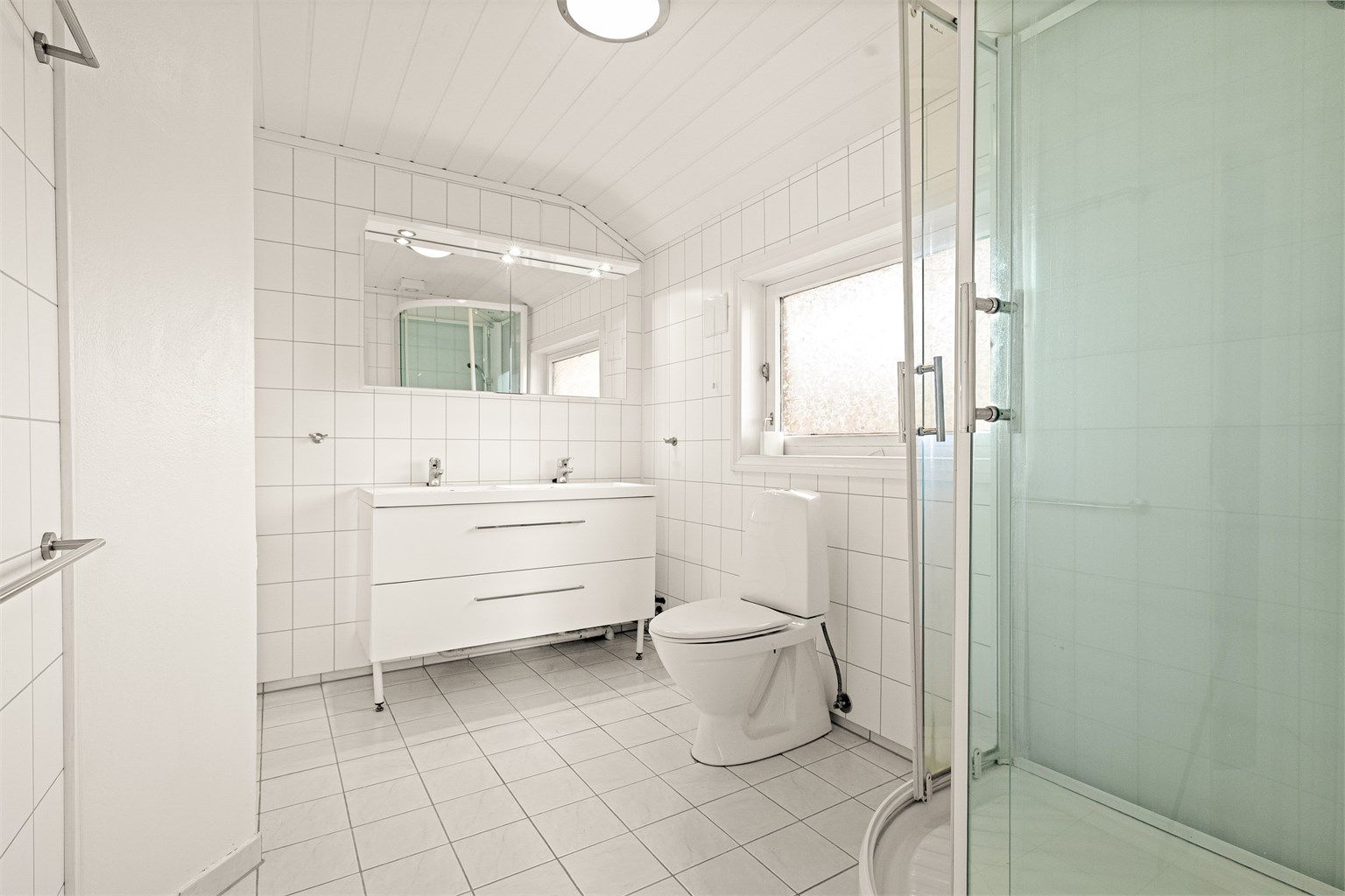 Baderom i loftsetasjen med baderomsplater på vegger og flislagt gulv med gulvvarme.