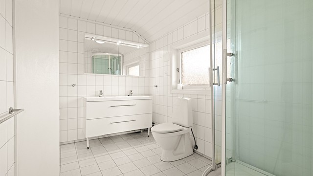 Baderom i loftsetasjen med baderomsplater på vegger og flislagt gulv med gulvvarme.