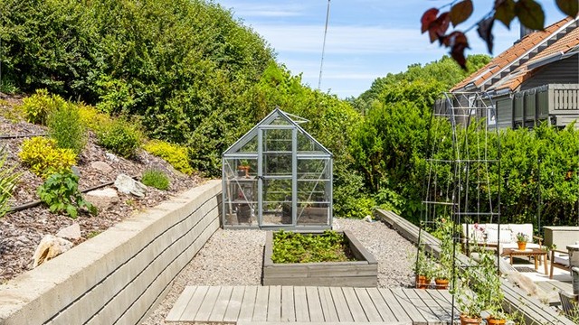 Støttemurer i betongstein tar opp nivåforskjellene på den skrånende tomten.