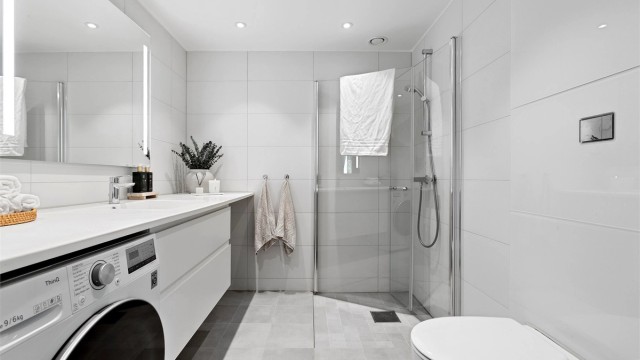Flislagt bad med elektrisk gulvvarme og opplegg for vaskemaskin.